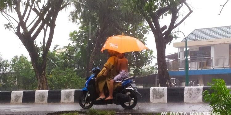 FOTO : DEVIANA/MATAKALTENG - Pengendara motor mengenakan payung saat kehujanan, Selasa 22 Februari 2022.