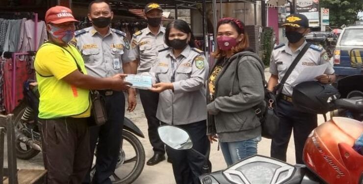 FOTO : IST/MATAKALTENG - Petugas Dinas Perhubungan Kabupaten Kotawaringin Timur membagikan masker dan vitamin kepada juru parkir di Kota Sampit, Kamis 17 Maret 2022.