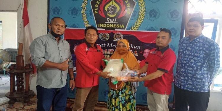 FOTO: ALDI SETIAWAN/MATA KALTENG: Ketua PWI Seruyan, M. Yadi (dua dari kiri) saat menyerahkan bantuan beras kepada salah satu warga membutuhkan di Kuala Pembuang, Kamis 21 April 2022.