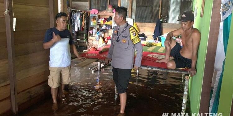 FOTO : SYIHAB/MATAKALTENG -   Bhabinkamtibmas Polres Kotim sedang memantau kondisi rumah warga yang terendam banjir