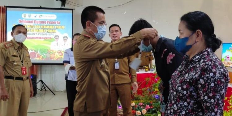 FOTO: IST/MATAKALTENG - Sekda Murung Raya Dr Hermon, MSi saat memasang tanda peserta kegiatan Pelatihan mutu dan keamanan pangan Dinas Ketahanan Pangan, Selasa 24 Mei 2022.