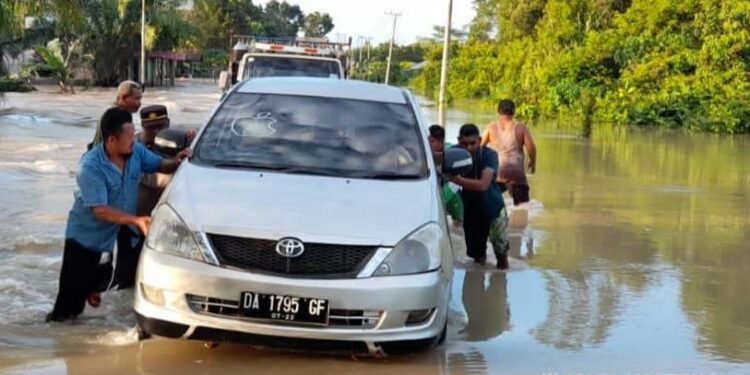Kapolsek Pangkalan Banteng Iptu Faisal Firman Gani bersama Koramil dan pemerintah kecamatan setempat membantu kendaraan terjebak banjir, Kamis, 30 Juni 2022