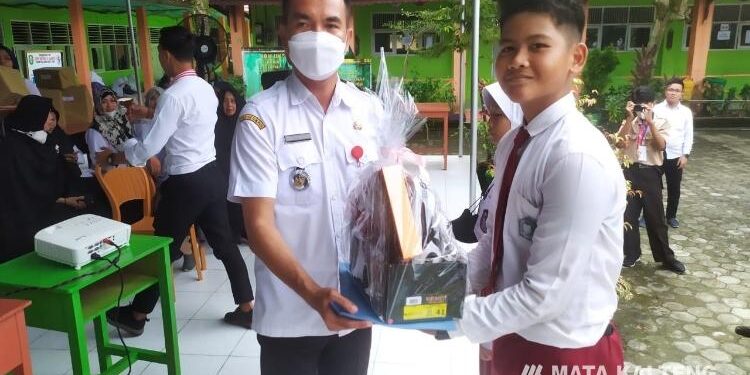 FOTO : SMPN 2 Sampit/MATA KALTENG - Camat MB Ketapang Eddy Hidayat Setiadi saat memberikan bingkisan kepada salah seorang siswa baru.