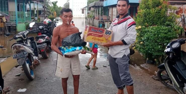 FOTO : Pemdes Bukit Batu/MATA KALTENG - Kepala Desa Bukit Batu, Kecamatan Cempaga Hulu, Ahmad (kanan) menyerahkan bantuan sembako kepada warga terdampak banjir.