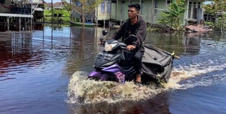 FOTO : OLIVIA/MATAKALTENG - Salah seorang pengendara roda dua menerjang banjir di Kota Palangka Raya