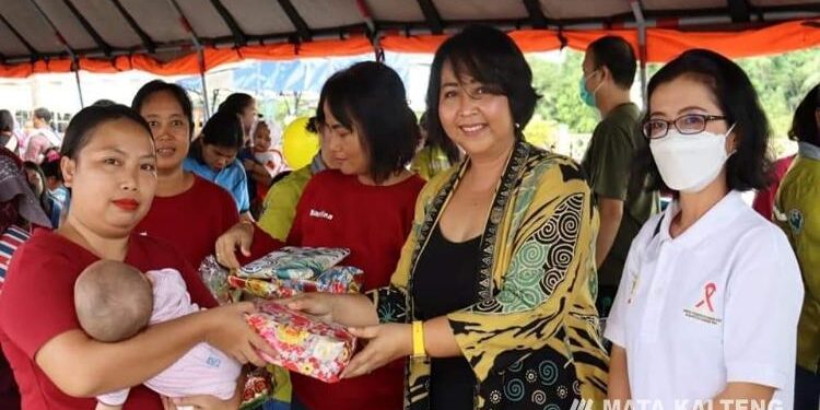 FOTO : ICEU PURNAMASARI/MATA KALTENG - Anggota DPRD Kabupaten Gumas Iceu Purnamasari (batik kuning) membagikan makanan tambahan kepada warga yang mengikuti posyandu akbar, di Taman Kota Kuala Kurun, Jumat 18 November 2022.
