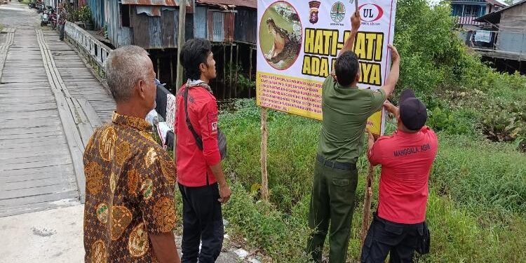 FOTO : IST/MATAKALTENG - Petugas BKSDA Pos Jaga Sampit dan Mnaggala Agni memasang papan peringatan keberadaan buaya di muara Sungai Mentawa, Kecamatan MB Ketapang, Selasa, 10 Januari 2023.