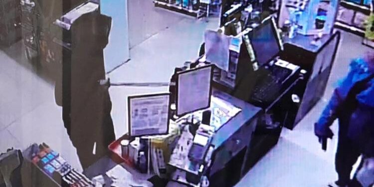 Tangkapan layar rekaman kamera pengawas, pada saat pelaku (menggunakan baju hitam) menodongkan parang kepada karyawan Alfamart.