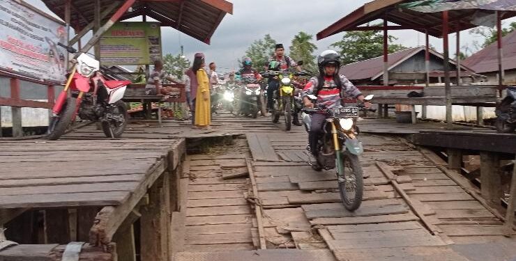 FOTO : DEVIANA /MATAKALTENG - Warga saat melintasi dermaga penyebrangan Kecamatan Seranau menuju Kota Sampit yang sebagian kayunya telah gapuk, Jumat 13 Januari 2023.