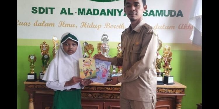 Foto: SD IT Al Madaniyah/MATA KALTENG - Seorang siswa menyerahkan buku karya tulisnya kepada Kepala SDIT Al-Madaniyah, Mutaqin Saufi.