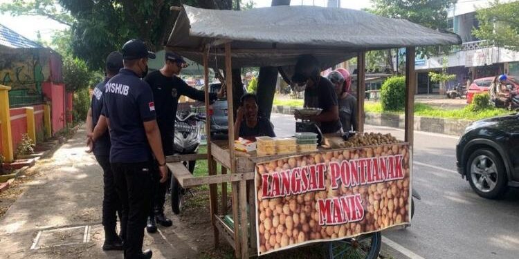 FOTO: MMC/MATAKALTENG - Personel Dishub mendatangi satu per satu PKL yang sedang jualan di atas drainase dan trotoar di sepanjang Jalan Ahmad Yani. 