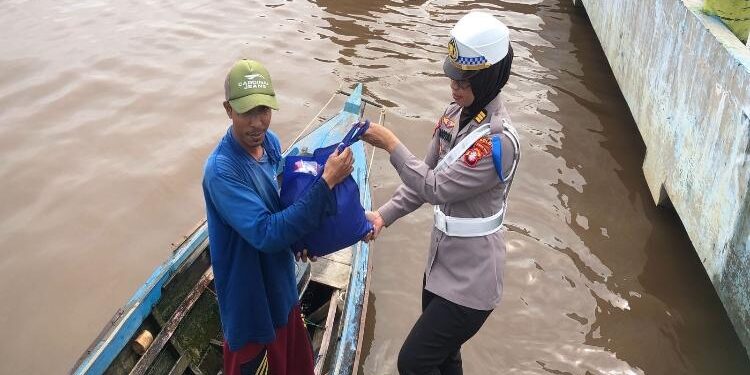 FOTO: RIZAL/MATAKALTENG - Personel Ditlantas Polda Kalteng, pada saat menyerahkan sembako kepada warga di bantaran Sungai Kahayan.