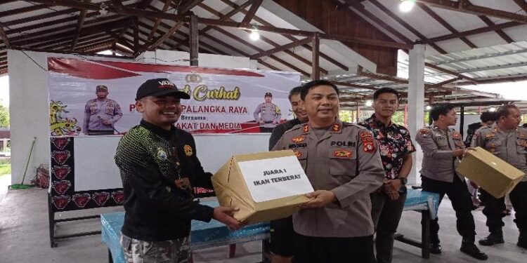 Penyerahan hadiah juara ikan terberat I, dari Wakapolresta Palangka Raya, AKBP Andiyatna, kepada pemenang Syahrul Mubarak.