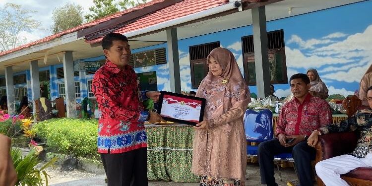 FOTO: DIAN TARESA/MATA KALTENG - Kepala SMPN 3 Sampit, Siti Khadijah saat menerima penghargaan yang diserankan oleh Plt Kepala Disdik Kotim, Irfansyah.