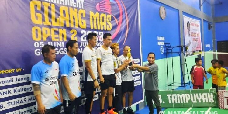 FOTO : SID/MATA KALTENG - Anggota DPRD Kabupaten Gumas Evandi saat menyerahkan piala dan uang pembinaan kepada para juara turnamen gilang Mas Open 2 tahun 2023, di GOR GSS Kuala Kurun, Senin 12 Juni 2023 malam.