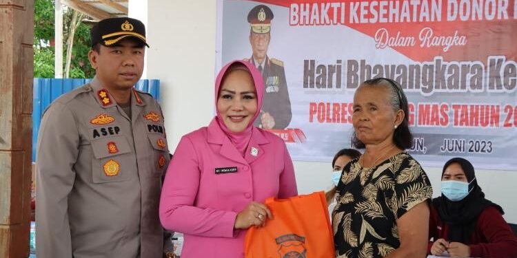 FOTO: HUMAS POLRES GUMAS/MATAKALTENG - Ketua Bhayangkari Cabang Gumas, Indah Asep bersama Kapolres Gumas, AKBP Asep Bangbang Saputra, saat menyerahkan bingkisan kepada warga, pada kegiatan bakti sosial menyambut hari Bhayangkara ke-77, di Taman Kota Kuala Kurun, Rabu, 7 Juni 2023.