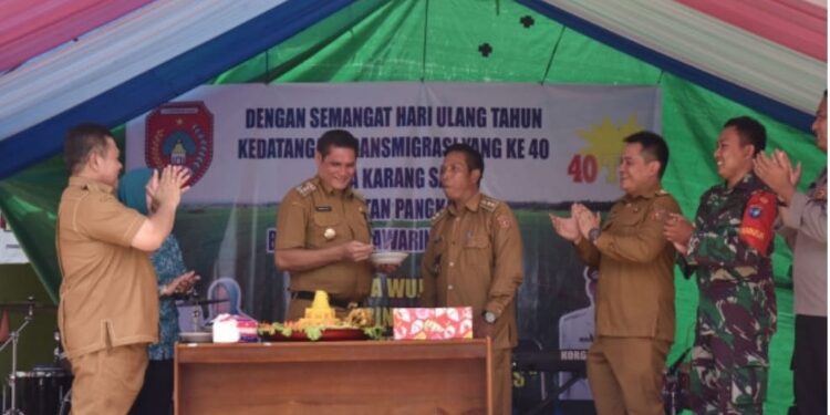 FOTO: IST/MATAKALTENG - Pj Bupati Kobar Anang Dirjo menerima tumpeng peringatan 40 awal kedatangan warga Transmigrasi Desa Karang Sari, Kecamatan Pangkalan Banteng.