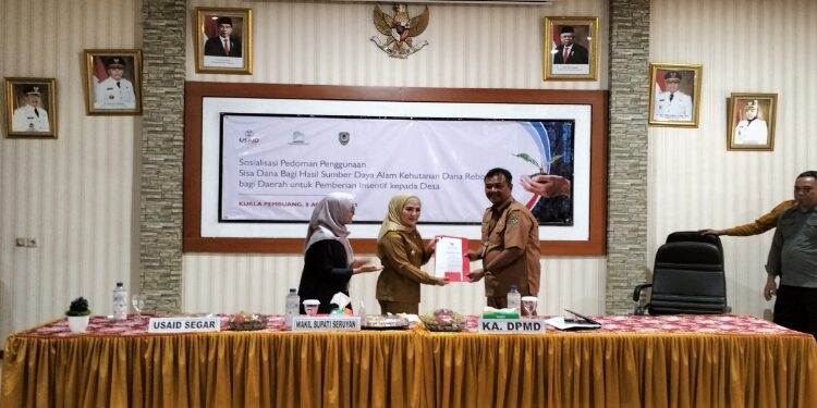 FOTO: ALDI/MATA KALTENG - Wakil Bupati Seruyan, Iswanti (tengah) saat menyerahkan secara simbolis Perbub terkait penggunaan DBHDR dalam agenda sosialisasi pedoman penggunaan DBHDR bagi daerah untuk pemberian insentif kepada desa (kades) di Aula BKAD Seruyan, Selasa 8 Agustus 2023.