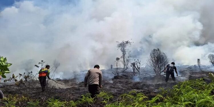 FOTO : IST/MATA KALTENG - Aparat kepolisian dibantu warga melakukan pemadaman api yang menghanguskan sejumlah lahan, agar api tidak meluas, belum lama ini.