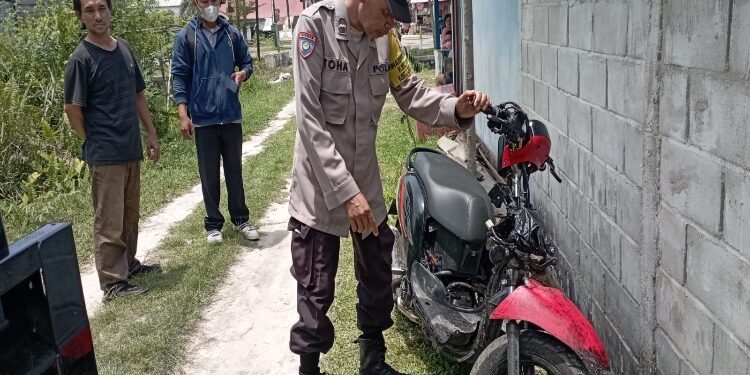 FOTO: RZL/MATAKALTENG - Bhabinkamtibmas Kelurahan Menteng, Aiptu Toha, saat mengevakuasi sepeda motor tak bertuan.
