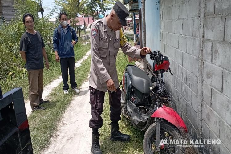 FOTO: RZL/MATAKALTENG - Bhabinkamtibmas Kelurahan Menteng, Aiptu Toha, saat mengevakuasi sepeda motor tak bertuan.
