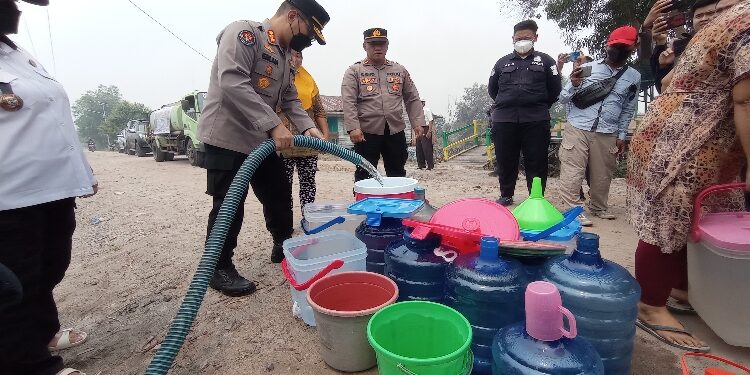 FOTO: RZL/MATAKALTENG - Kabid Humas Polda Kalteng, Kombes Pol Erlan Munaji, saat mengisi air bersih ke tangki warga.