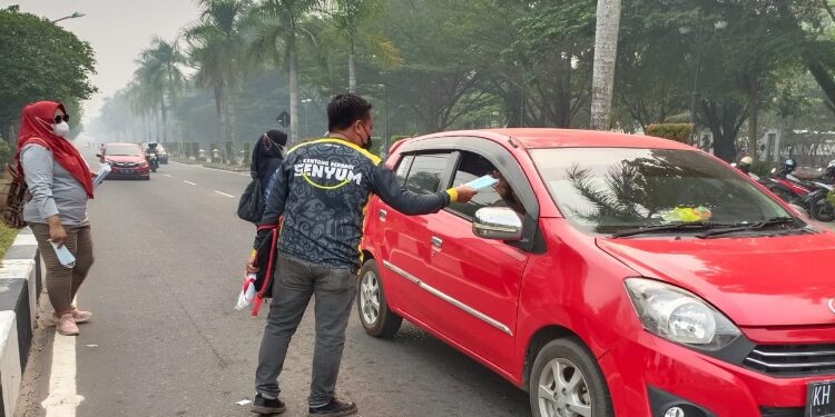 FOTO: MATAKALTENG - Komunitas Kantong Berbagi senyum saat membagikan 5.000 lembar masker di Jalan Yos Sudarso.