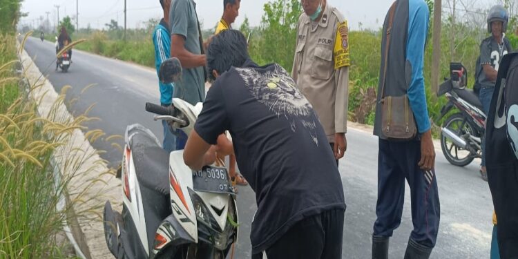 FOTO: MATAKALTENG - Bhabinkamtibmas Menteng, Aiptu Toha, saat mengevakuasi sepeda motor tak bertuan.