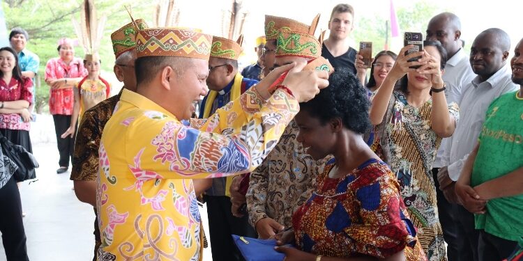 FOTO: DISKOMINFOSANTIK/MATA KALTENG - Bupati Gumas Jaya S Monong didampingi forkopimda menyambut kedatangan rombongan lembaga gereja internasional UEM, dengan memasangkan topi adat Dayak, di Gedung Christian Center Kuala Kurun, Kamis 12 Oktober 2023.