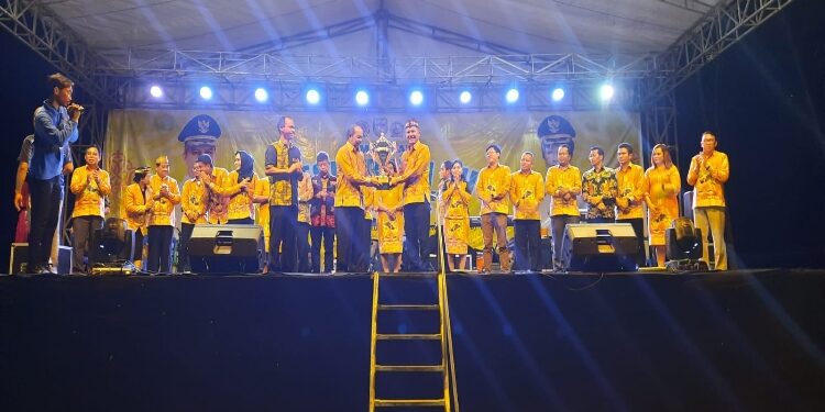 FOTO : DISKOMINFO SANTIK/MATA KALTENG - Bupati Gumas Jaya S Monong ketika menyerahkan piala juara umum kepada Ketua Panitia Lurand, untuk diperebutkan seluruh kontingen Pesparawi VII tingkat kabupaten tahun 2023, di Kelurahan Tumbang Napoi, Kecamatan Miri Manasa, Rabu, 25 Oktober 2023 malam.