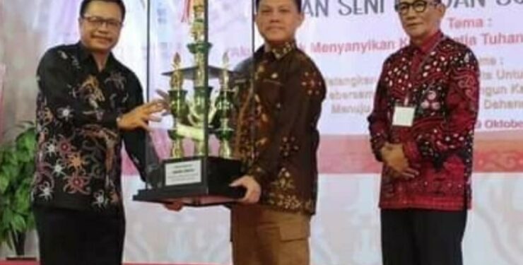 FOTO : IST/MATAKALTENG - Pj. Bupati Barsel Deddy Winarwan saat mengangkat piala bergilir yang diperebutkan di ajang Pesparawi IX tingkat kabupaten Barsel.