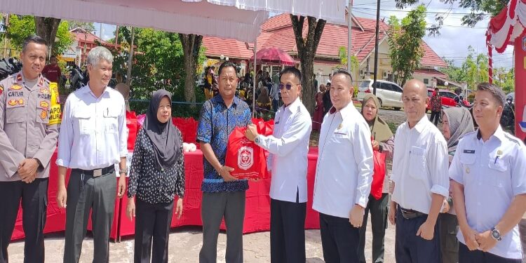 FOTO : ZON/MATAKALTENG - Pj Bupati Murung Raya Hermon  (kacamata hitam) saat menyerahkan secara simbolis paket sembako murah kepada warga.