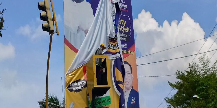 FOTO: RZL/MATAKALTENG - Petugas gabungan saat menertibkan baliho milik saah seorang caleg yang melanggar aturan.