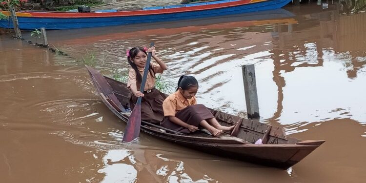 FOTO: MATAKALTENG - Para siswa di Kelurahan Kameloh Baru, pada saat hendak berangkat sekolah menggunakan perahu kayu.