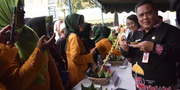 FOTO: IST/MATAKALTENG - Plh Sekda Kobar Juni Gultom saat mencicipi kue (wadai) dalam Festival Mehampar Wadai 2023, Minggu 29 Oktober 2023.