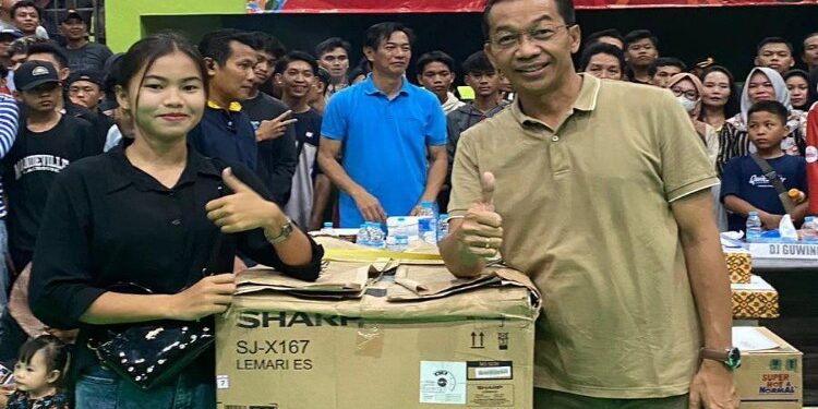 FOTO: MATAKALTENG - Bupati Murung Raya (Mura), Perdie M.Yoseph menyerahkan satu unit kulkas kepada salah satu penonton yang beruntung atas pengundian doorpize pada penutupan turnamen bola voli Bupati Cap tahun 2023 di gedung Tana Malai Tolung Lingu (TMTL) Puruk Cahu, Kamis (14/9/2023).