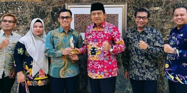 FOTO: IST/MATAKALTENG - Pj Bupati Kobar berswafoto saat memegang piala penghargaan Pahari Award dari BI.