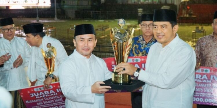 FOTO: IST/MATAKALTENG - Penjabat Bupati Kobar Budi Santosa menerima piala mewakili Kobar sebagai juara umum MTQH XXXI tingkat provinsi Kalteng.