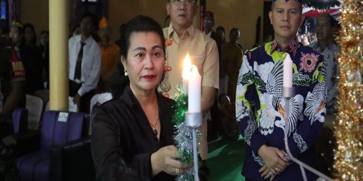 FOTO : MATA KALTENG - Anggota DPRD Kabupaten Gumas Rayaniatie Djangkan ketika menyalakan lilin pada kegiatan safari natal pemkab tahun 2023, di Kelurahan Kampuri, Kecamatan Mihing Raya, Kamis, 7 Desember 2023.