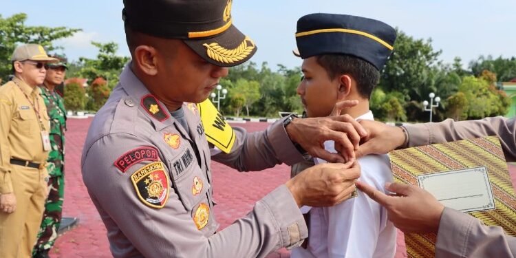 FOTO : HUMAS POLRES GUMAS/MATA KALTENG - Wakapolres Gumas Kompol Tri Wibowo didampingi Sekda Richard, ketika menyematkan pita kepada perwakilan personel sebagai tanda dimulai operasi lilin telabang tahun 2023 pada apel gelar pasukan, Kamis, 21 Desember 2023.