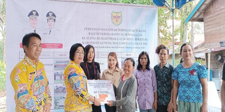 FOTO : DISKOMINFO SANTIK/MATA KALTENG - Wakil Bupati Gumas Efrensia LP Umbing bersama Kepala DPU Baryen saat menyerahkan secara simbolis upah tukang bagi kepada penerima BPKRTLH, di Kelurahan Tampang Tumbang Anjir, pekan lalu.