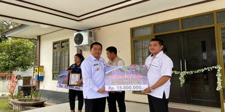 FOTO: AKH/MATAKALTENG - Pj Bupati Sukamara Kaspinor menyerahkan bonus kepada desa berprestasi dalam pungutan PBB-P2.