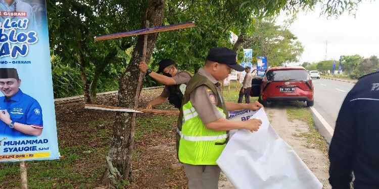 FOTO: RZL/MATAKALTENG - Tim gabungan saat menertibkan salah satu APK yang melanggar aturan di Jalan Adonis Samad, Kota Palangka Raya.