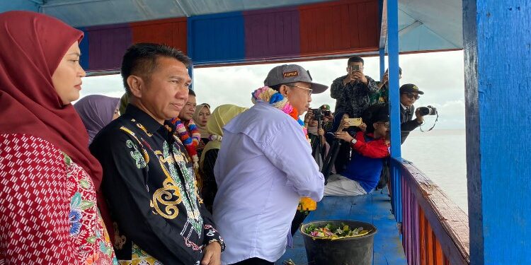 FOTO: AKH/MATAKALTENG - Pj Bupati Sukamara Kaspinor saat melakukan ritual tampung tawar yang ditandai dengan menyiramkan air Bungan dan beras kuning ke laut.