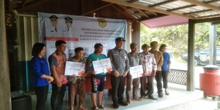 FOTO : DISKOMINFO SANTIK/MATA KALTENG - Bupati Gumas Jaya S Monong (pakai topi) didampingi Kepala DPU Baryen, saat berfoto bersama warga penerima program BPKRTLH, di Desa Sumur Mas, Kecamatan Tewah, belum lama ini.