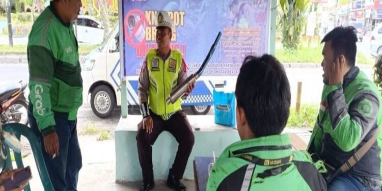 FOTO: RZL/MATAKALTENG - Anggota Ditlantas Polda Kalteng saat mensosialisasikan larangan penggunaan knalpot brong kepada para pengemudi Ojol.