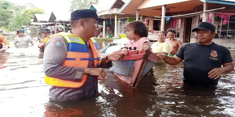 FOTO: IST/MATAKALTENG - Aparat kepolisian dan BPBD Barsel berjibaku membantu para warga Desa Kalahien yang mengalami kebanjiran.