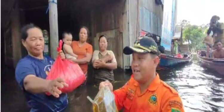 FOTO: IST/MATAKALTENG - Penjabat Bupati Barsel, Deddy Winarwan, saat memberikan bantuan sembako kepada warga yang terdampak banjir.