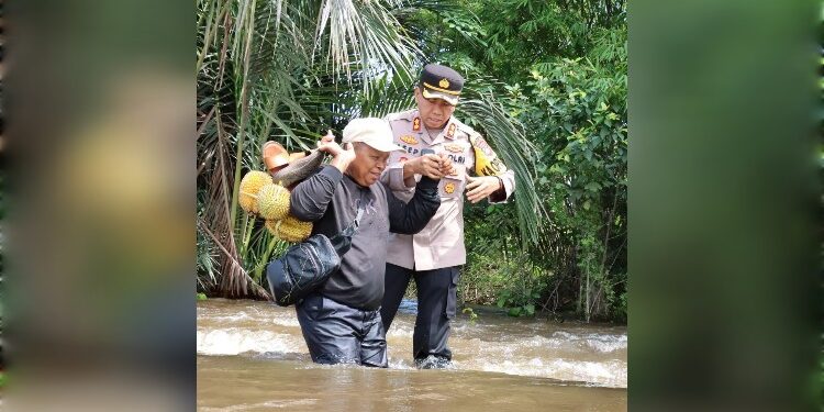 FOTO: IST/MATAKALTENG - Kapolres Barsel AKBP Asep Bangbang Saputra bersama sejumlah personel saat berupaya membantu warga melintasi jalan yang banjir.