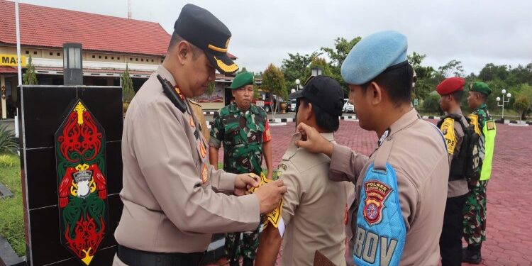 FOTO : HUMAS POLRES GUMAS/MATA KALTENG - Kapolres Gumas AKBP Theodorus Priyo Santosa bersama Sekda Richard, dan Pabung Kodim 1016/Plk Letkol Inf Maksun Abadi, memasang pita kepada personel yang akan melakukan pengamanan TPS pemilu tahun 2024, pada apel gelar pergeseran pasukan di halaman mapolres setempat, Senin, 12 Februari 2024.